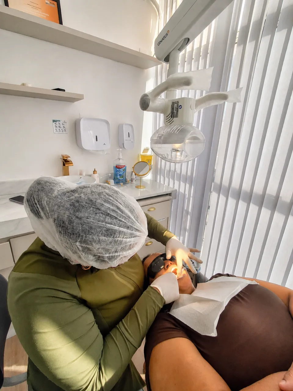 Dra. Juliana Laia realizando atendimento clínico em paciente na cadeira odontológica