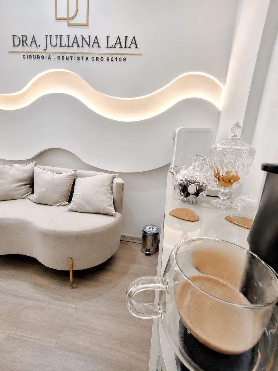 Recepção com sofá curvo, iluminação em LED e café servido aos pacientes